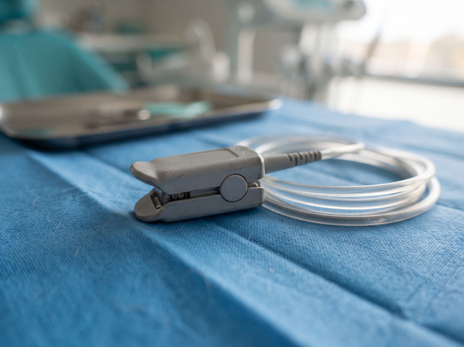 A pulse oximeter sensor and monitoring cable resting on a blue surgical drape at Hanover Dental Sedation